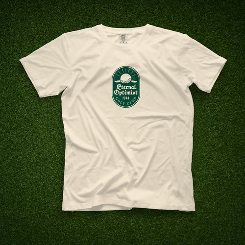 Ivory t-shirt with a green Eternal Optimist Golf Club logo. 