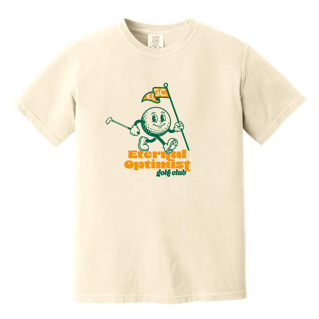 Ivory t-shirt with a 1950s-inspired golf ball cartoon that has legs and arms. He is carrying a putter and a flagstick that has "E.O.G.C." on the flag. Below him are the words 'Eternal Optimist Golf Club'.