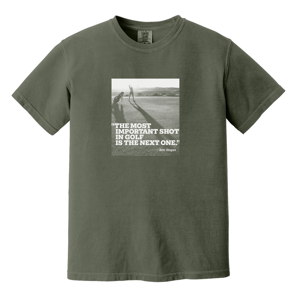 Mossy green t-shirt that has an image of a golfer with a quote from Ben Hogan: "The most important shot in golf is the next one."