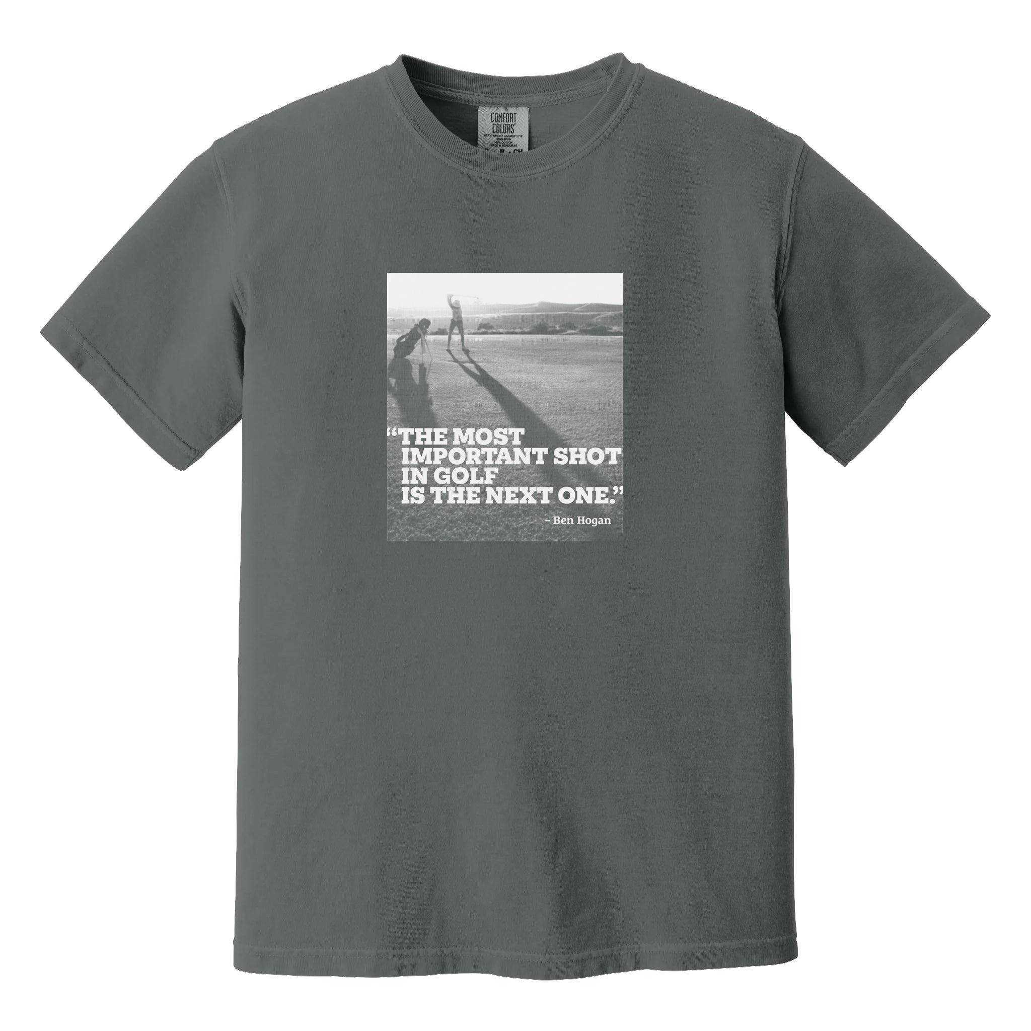 Dark gray t-shirt that has an image of a golfer with a quote from Ben Hogan: "The most important shot in golf is the next one."
