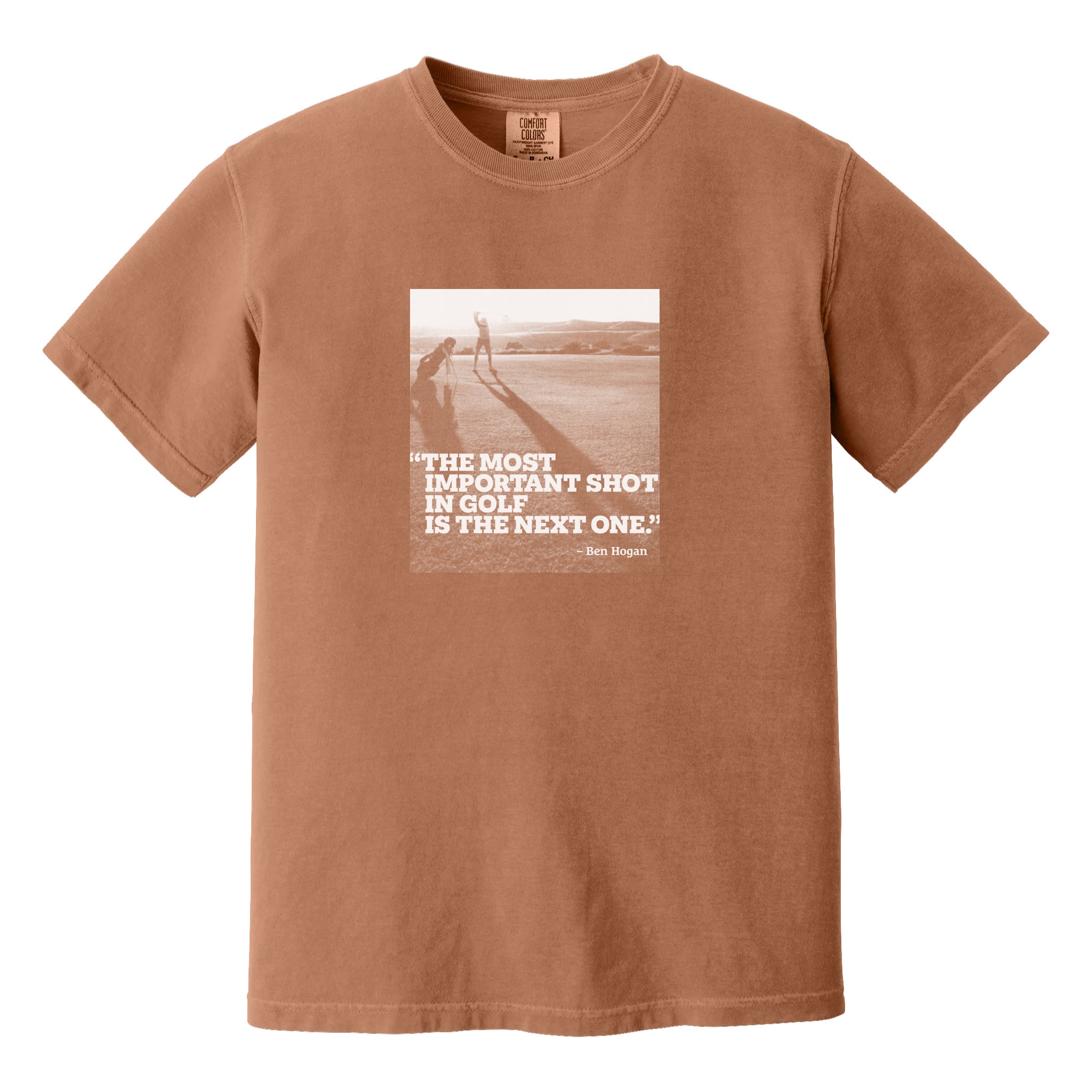 Dark orange t-shirt that has an image of a golfer with a quote from Ben Hogan: "The most important shot in golf is the next one."