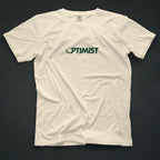 Ivory t-shirt with 'OPTIMIST' printed on it. The "O" in OPTIMIST has been replaced by a golf ball.