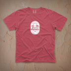 Dark pink t-shirt with a white Eternal Optimist Golf Club logo on a beige textured background.